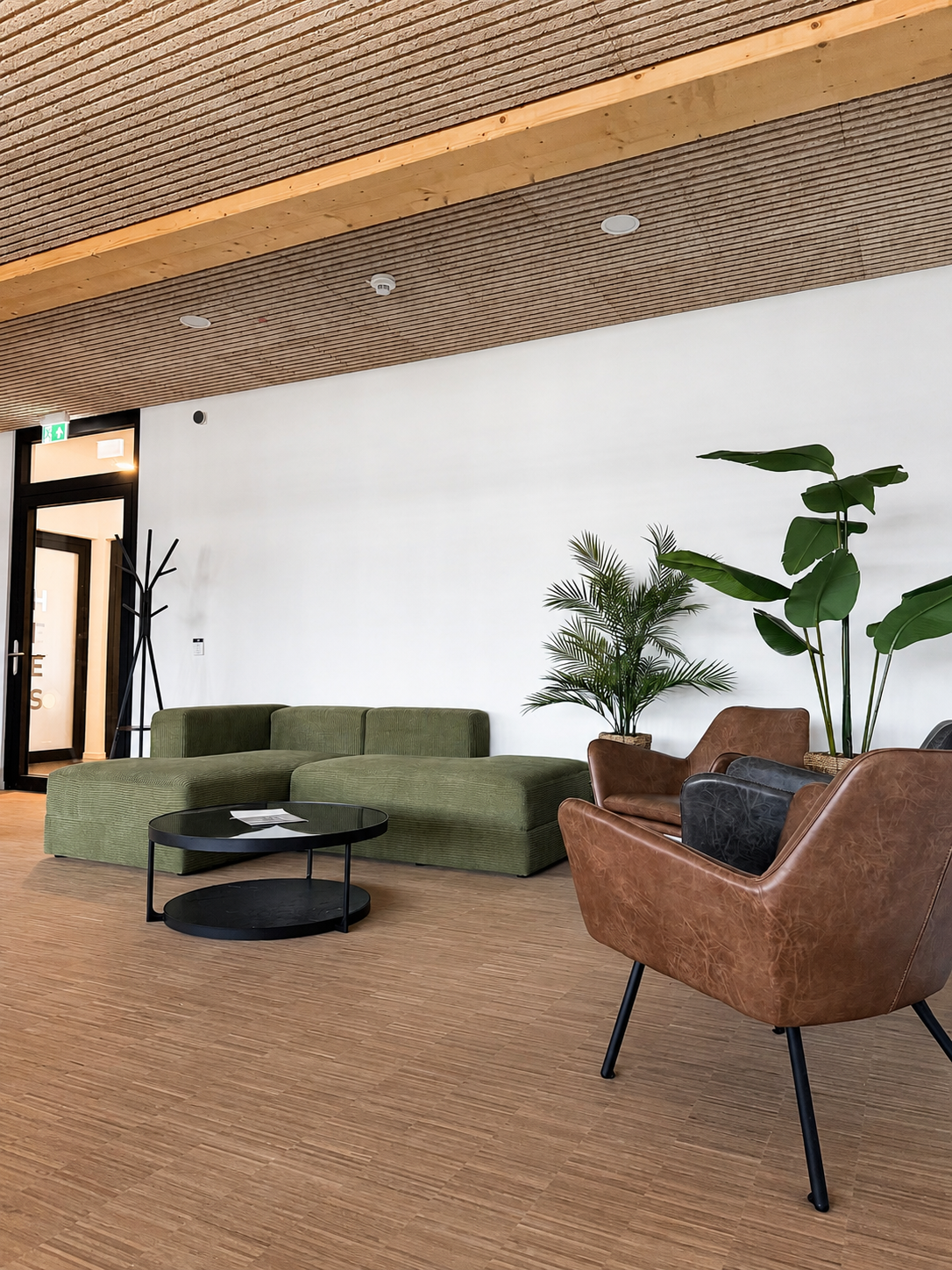 Gemütliche Lounge-Area der THINKBOX mit grüner Sitzlandschaft, Ledersesseln und Pflanzen