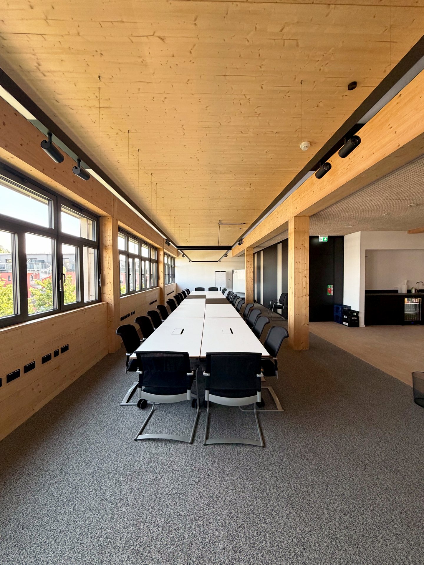 Großer Seminarraum der THINKBOX mit langer Konferenztafel, Holzdecke und Fensterfront