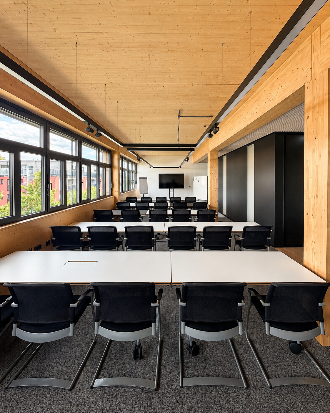 Seminarraum der THINKBOX mit Holzdecke, Fensterfront und Reihenbestuhlung für Tagungen